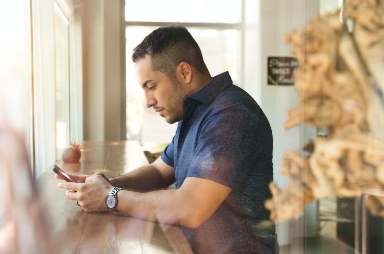 A man in a coffee shop looks at his phone