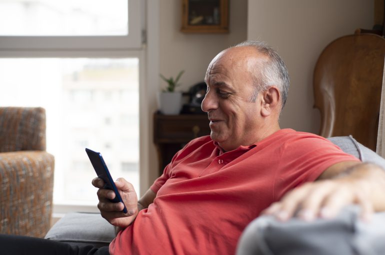 An older man looks at something on his phone.
